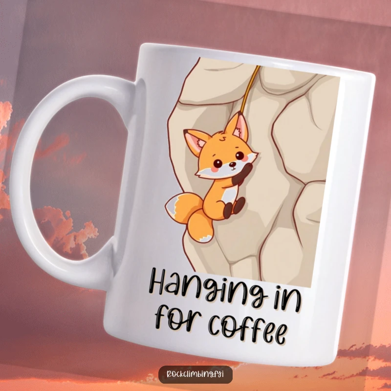 Funny playful fox dangling from a rock face by a tiny rope on a mug, showcasing humor and lighthearted peril.