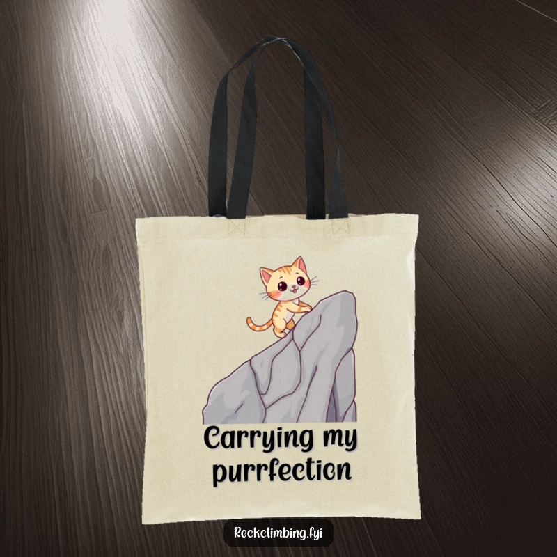Funny cat tote bag with a winking cat climbing a cliff, perfect for carrying essentials with a humorous touch.